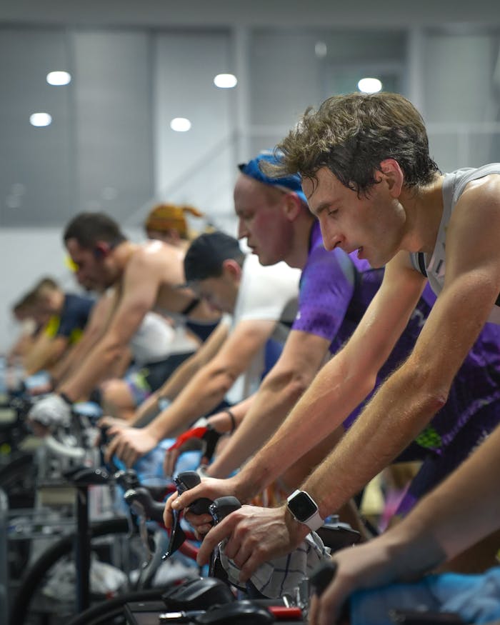 A group of people intensely focused during an indoor cycling class, showcasing fitness and teamwork.